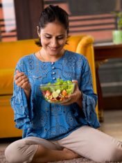Happy Indian woman eating fruit salad at home